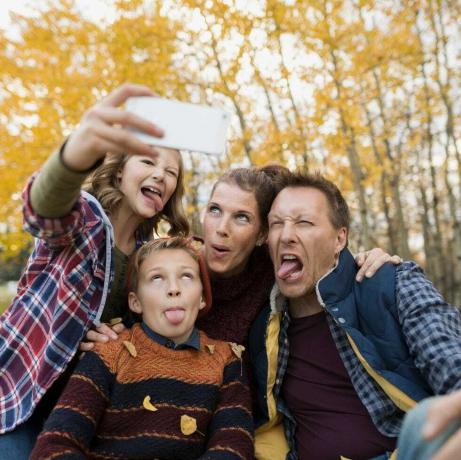 Domme familie die selfie maakt en gezichten maakt in het herfstpark