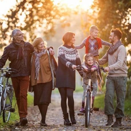 lachende familie van meerdere generaties die een wandeling maakt met fietsen in de natuur en geniet van hun tijd samen