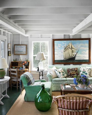 verzamelde woonkamer in Maine met een groene bank en een gigantische vintage scheepsschilderij aan de muur